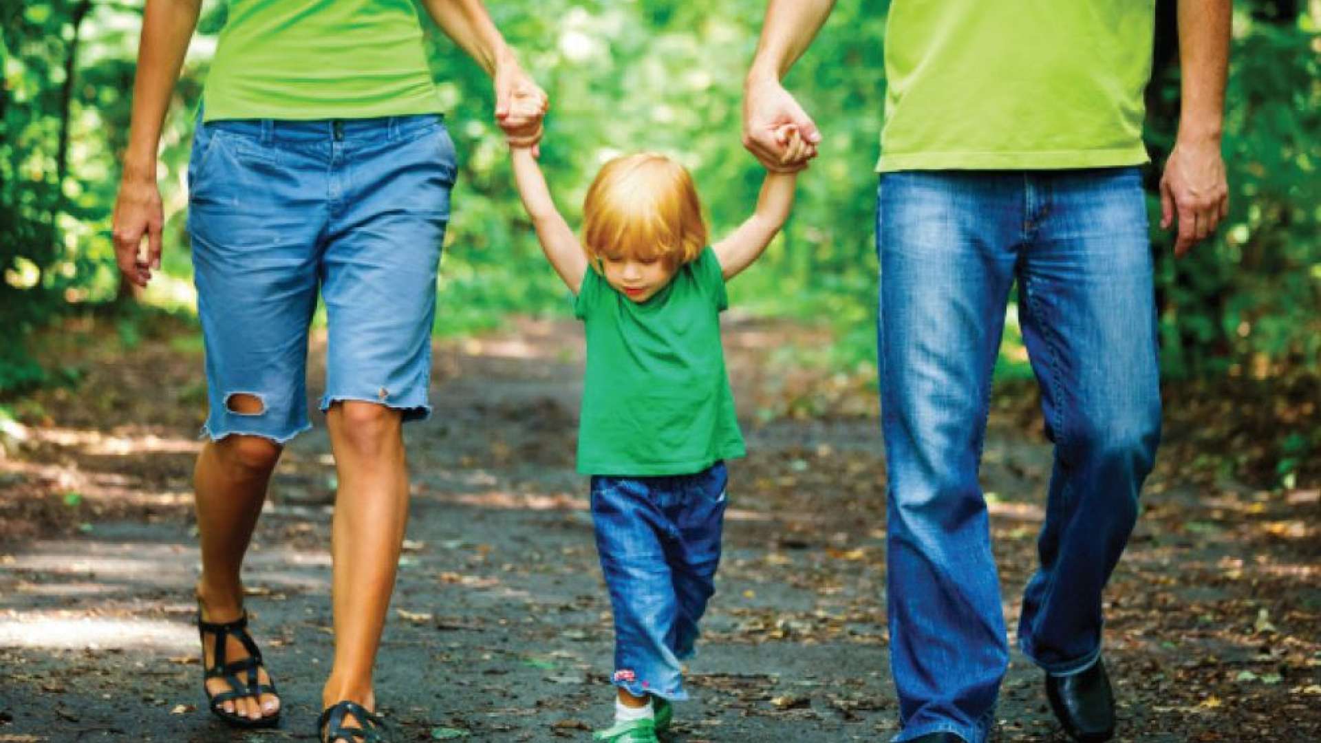 parents walk with their kid in the forest
