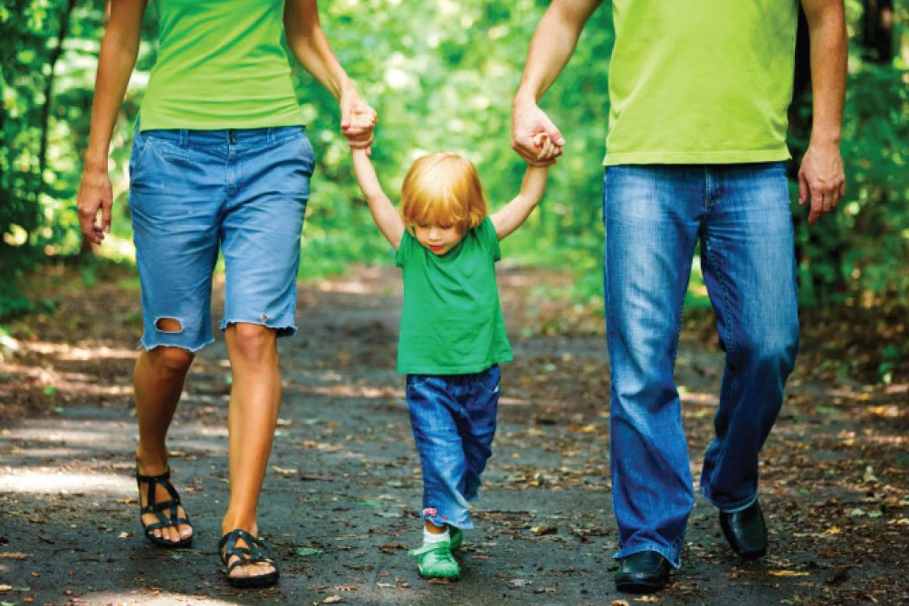 parents walk with their kid in the forest